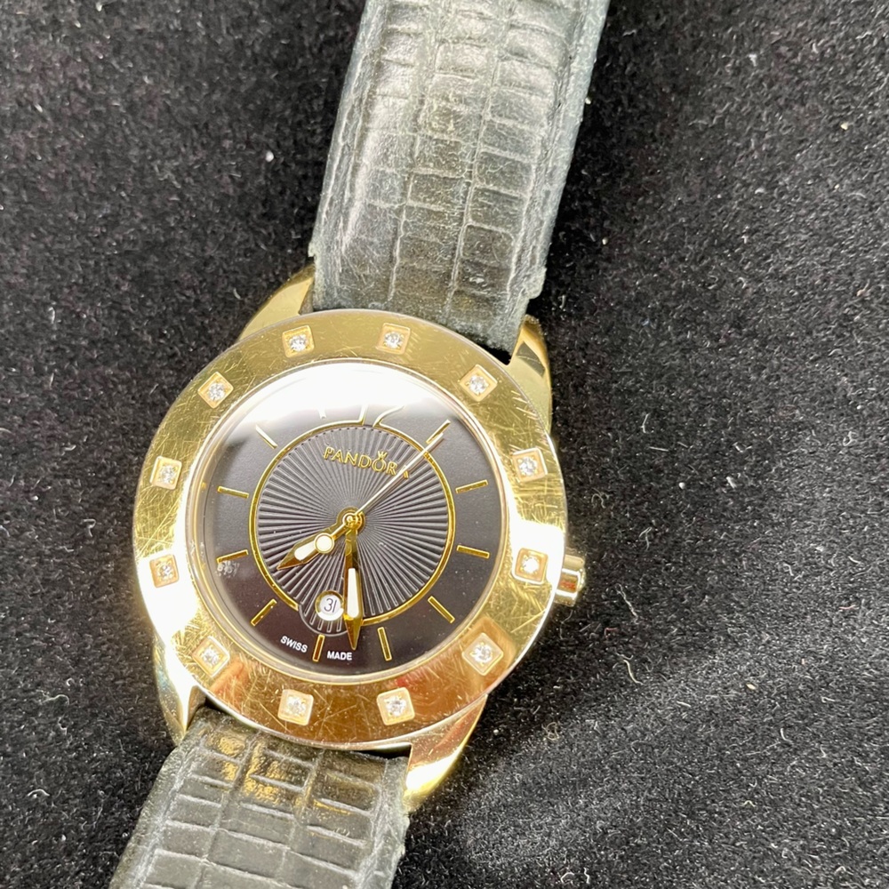 This is a Pandora 18K Gold watch with a black leather band and diamonds.